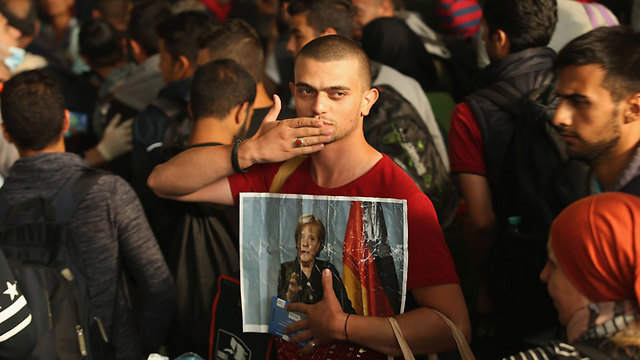 Syrian refugee holds Chancellor Merkel's photo at a railway station in Munich. Germany can deal with several million Syrian refugees demographically, but it can't necessarily deal with the long-term outcomes (Photo: Getty Images)