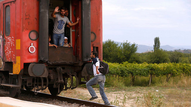 מהגר מנסה להספיק לעלות על רכבת שיוצאת ממקדוניה (צילום: רויטרס) (צילום: רויטרס)