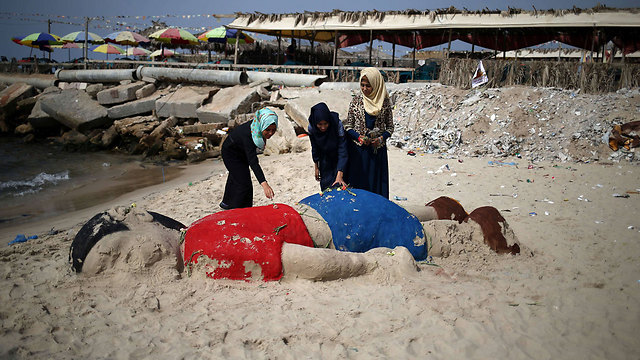חולקים כבוד לפעוט הסורי המת. פסל החול של איילן בחוף הים בעזה (צילום: AFP) (צילום: AFP)