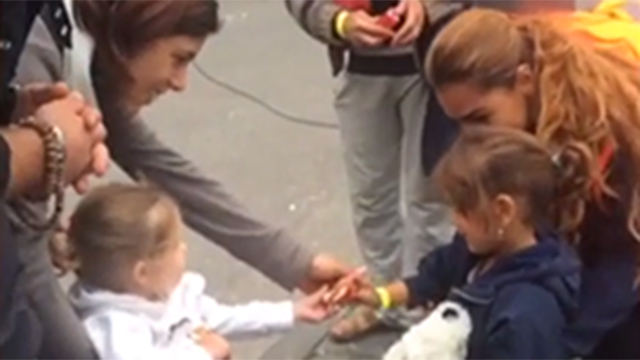 ילדה גרמנייה נותנת ממתק לילדה סורית בגרמניה ()