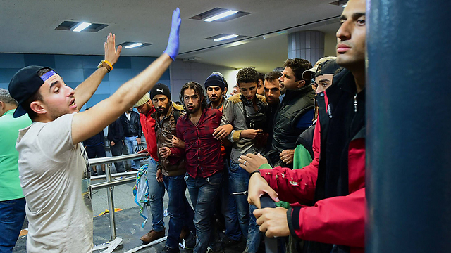 מתנדב מכוון פליטים בתחנת רכבת בבודפשט (צילום: AFP) (צילום: AFP)