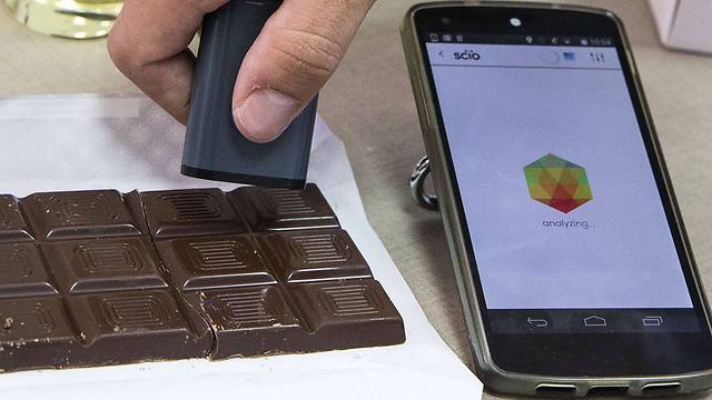 A staff of the Laboratory of the Consumer Physics Society performs a test on a chocolate bar using SCIO (Photo: AFP)