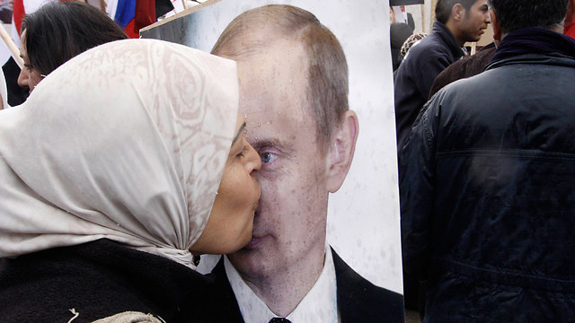 אישה סורית מנשקת את תמונת פוטין מול שגרירות רוסיה בדמשק (צילום: AP) (צילום: AP)