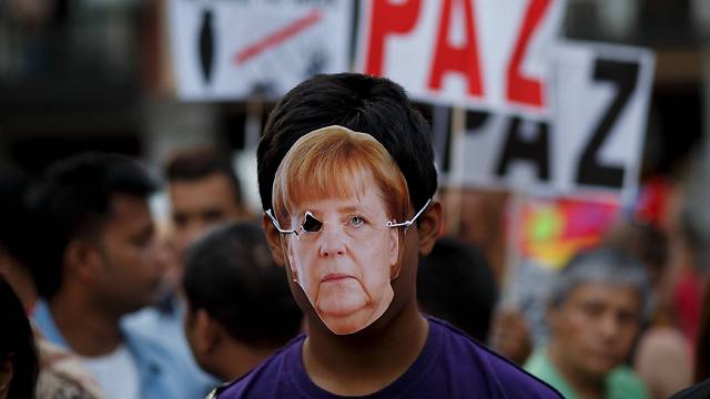 מסכת מרקל בהפגנת תמיכה בפליטים במדריד (צילום: Getty Images) (צילום: Getty Images)
