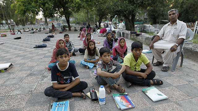 תלמידי כיתה ה' בשיעור בפארק באיסלמבד בפקיסטן. המורה, איוב, מלמד בפארק כשמזג האוויר נעים. בחודשי החורף עוברים התלמידים לחדר בשכונת עוני באיסלמבד (צילום: רויטרס) (צילום: רויטרס)
