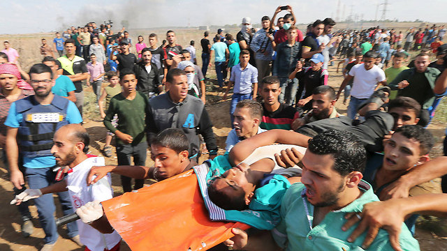 Palestinians carry an injured rioter (Photo: Reuters)