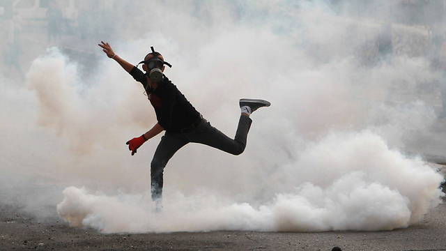 A young Palestinian demonstrator throws back tear gas that was fired by the IDF in Bethlehem (Photo: AFP)