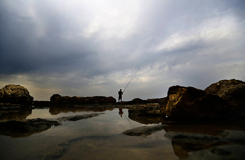 דייג דג תחת השמיים של ביירות בימי האובך בלבנון (צילום: AP) (צילום: AP)