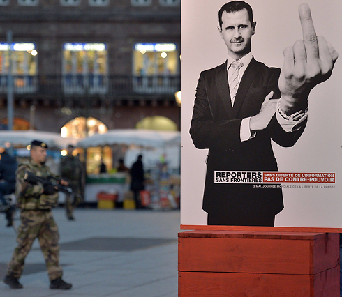 כרזה של "רופאים ללא גבולות" בפריז: אסד עם אצבע משולשת (צילום: AFP) (צילום: AFP)