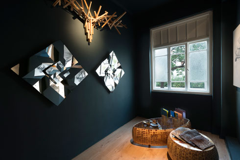 בגלריה החדשה. על קירות שחורים מוצגות עבודות אוריגמי בנירוסטה של אילן גריבי, ומתלה המעילים של ג'וי ואן ארוון (צילום: גדעון לוין)