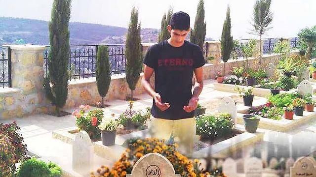 המחבל אחמד ג'מאל טה על קברו של קרוב משפחתו שדקר באותו מקום ()