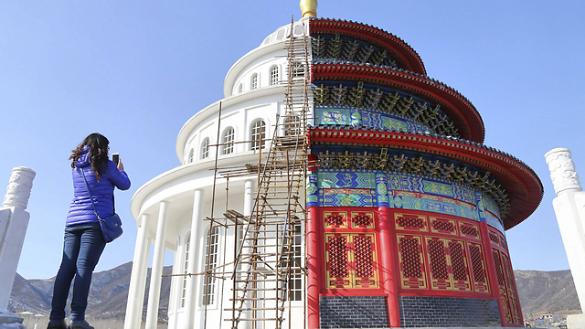 אישה מצלמת בניין שחציו האחד העתק של מקדש השמיים בבייג'ינג וחציו השני בניין מערבי בעיר הסינית שה-ג'יאנג'וואנג, בירת מחוז חביי (צילום: רויטרס) (צילום: רויטרס)