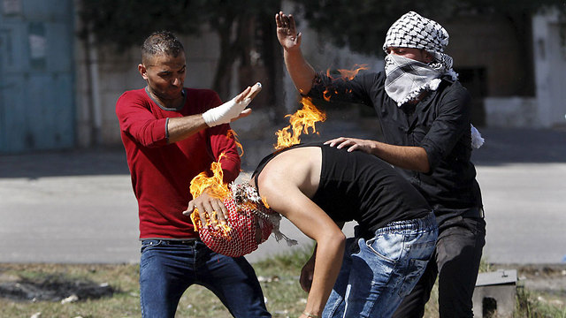 פלסטינים מנסים לכבות את האש שאחזה במפגין פלסטיני שניסה לזרוק בקבוק תבערה על כוחות צה"ל - ופגע בטעות בעצמו (צילום: רויטרס) (צילום: רויטרס)
