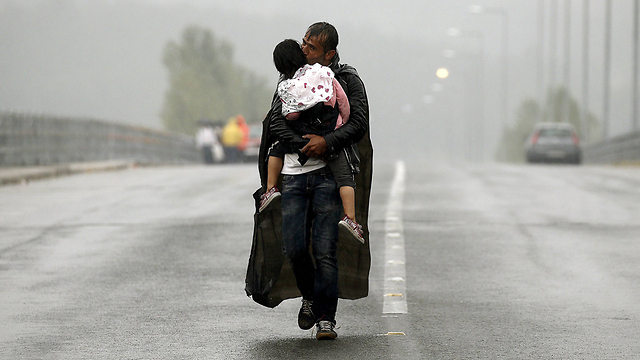 פליט סורי נושא את בתו על ידיו, בדרך מיוון למקדוניה (צילום: רויטרס) (צילום: רויטרס)