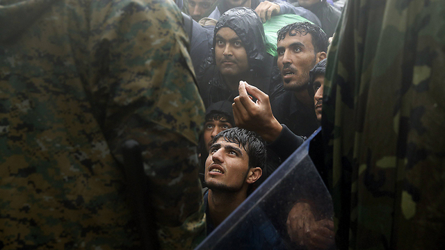 תחת גשם שוטף, מהגרים מתחננים בפני כוחות הביטחון שיאפשרו להם לחצות את הגבול מיוון למקדוניה, בדרכם למערב אירופה (צילום: רויטרס) (צילום: רויטרס)