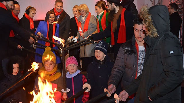 Syrian refugee children light candles alongside Jewish children