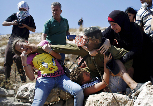 חייל צה"ל נאבק בפלסטינים המנסים למנוע ממנו לעצור ילד שהתפרע בזמן הפגנה בשטחים (צילום: רויטרס) (צילום: רויטרס)