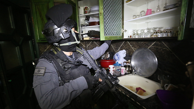 A Yasam police officer searching a suspect's house in Anata village. (Photo: Gil Yohanan)