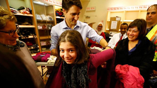 Trudeau gives a refugee a warm winter coat (Photo: Reuters) 