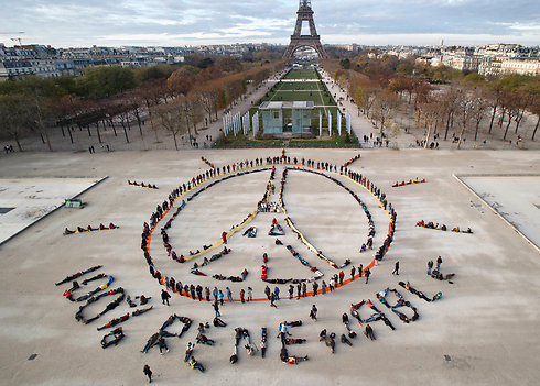 פעילי סביבה יוצרים שרשרת אנושית בצורת סמל השלום ליד מגדל אייפל בפריז, העיר שבה חתמו 195 מדינות על הסכם היסטורי להפחתת פליטת גזי החממה (צילום: AP) (צילום: AP)