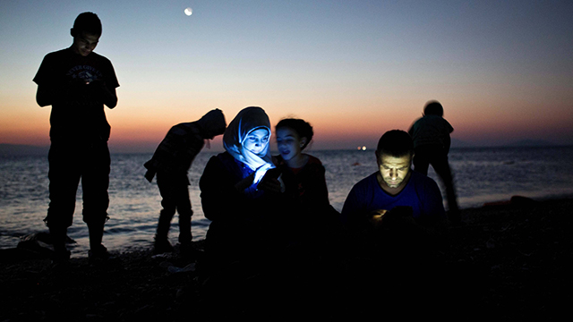 מהגרים בודקים את הטלפון הסלולרי שלהם עם הגיעם ליוון (צילום: AFP) (צילום: AFP)