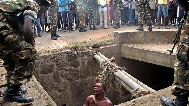 גבר בתעלת ניקוז בבורונדי מתחנן לחיילי הצבא שיחלצו אותו, אחרי שנמלט וניצל מלינץ' (צילום: AFP) (צילום: AFP)