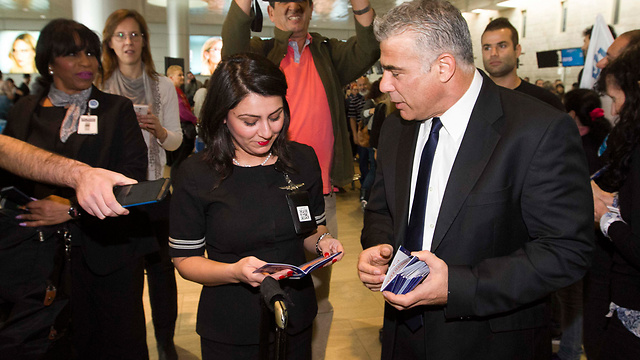 Yesh Atid head Yair Lapid at Ben Gurion Airport with Israelis about to fly abroad, distributing booklets on how to fight BDS. (Photo: Ido Erez)