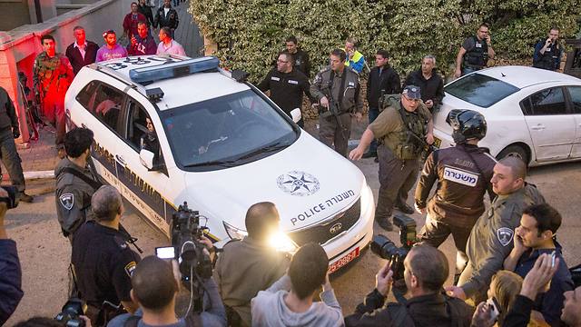 שוטרים הוציאו את המחבל בניידת משטרה מחצר הבית שאליו נמלט (צילום: AFP) (צילום: AFP)