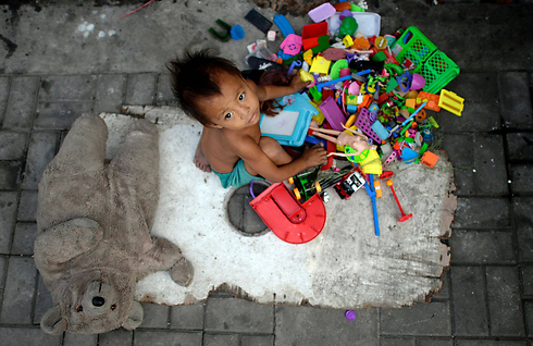 פעוט חסר בית משחק בצעצועים במנילה, הפיליפינים (צילום: AFP) (צילום: AFP)