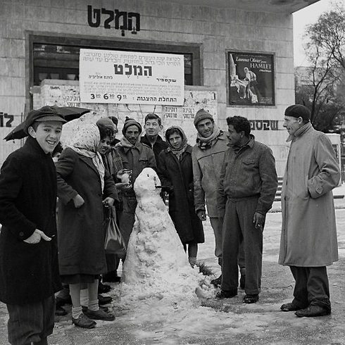 Passersby pose with a snowman in front of the historic Mograbi Cinema, showing "Hamlet" starring Laurence Olivier, on February 6, 1950 (Photo: David Eldan/GPO)