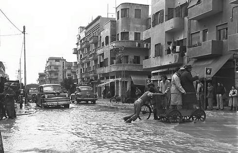 People cross the street on a cart on a flooded Shalma Street, 1949 (Photo: Fritz Cohen/GPO) 