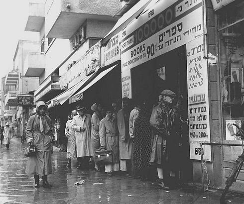 Crowd waits in the rain outside bookstore at 64 Allenby Street, offering books in Hebrew, English, Polish and French at a 90 percent discount, 1955 (Photo: Fritz Cohen/GPO)