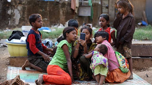 ילדים חסרי בית צופים בסרט בטלפון הסלולרי במומבאי, הודו (צילום: EPA) (צילום: EPA)