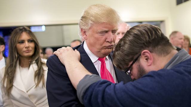Donald Trump prays with supporter shortly before the caucus (Photo: AP)