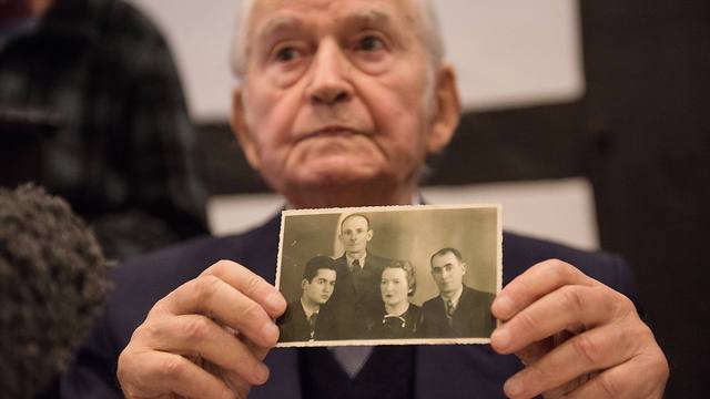 Auschwitz concentration camp survivor Leon Schwarzbaum presents an old photograph showing himself, left, next to his uncle and parents who all died in Auschwitz (Photo: AP)