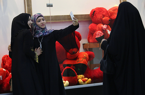 נשים עיראקיות בתמונת סלפי מול חנות מתנות בבצרה, עיראק (צילום: AFP) (צילום: AFP)