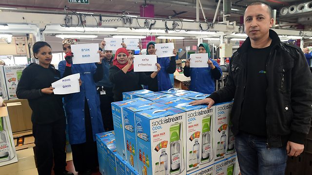 Ali Jafar with the women of the factory, who are holding up signs with the names of the Palestinian workers who will have to leave at the end of February (Photo: Haim Horenstein)
