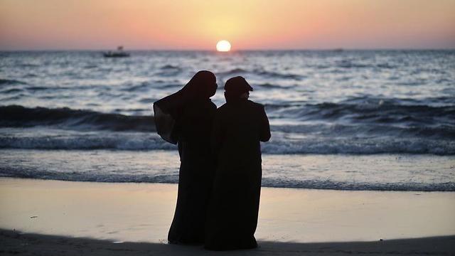 Palestinian women stand on a beach in Gaza City during sunset on summer's day (Photo: Reuters/Archive)