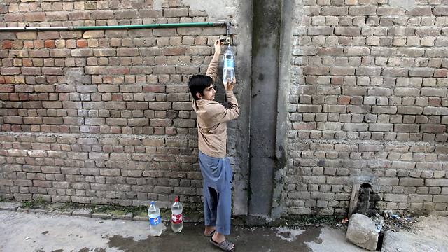 ילד ממלא בקבוק בצינור בפרברי איסלמבד, פקיסטן (צילום: רויטרס) (צילום: רויטרס)