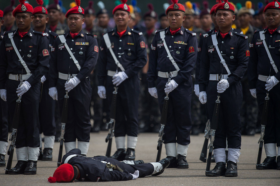 חבר ביחידת המילואים הפדרלית של מלזיה התעלף מהחום הכבד במהלך צעדת יום המשטרה ה-209 (צילום: AFP) (צילום: AFP)