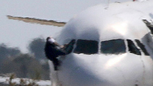 איש צוות בורח מחלון המטוס, מעט לפני סיום המשבר (צילום:רויטרס) (צילום:רויטרס)