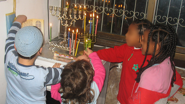 Children of all facets of society lighting Hannukah candles together.