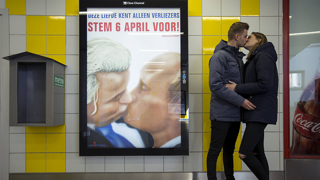 בני זוג מתנשקים ליד תמונתם של פוטין והלאומן ההולנדי חרט וילדרס "מתנשקים" גם הם, במטרו של אמסטרדם (צילום: רויטרס) (צילום: רויטרס)