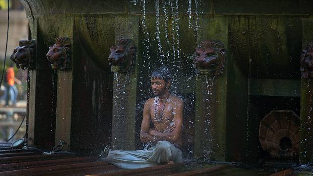 מיליוני הודים סובלים מהחום הכבד ואחד מהם מצא דרך להתרענן - מתחת למזרקה ציבורית בניו דלהי (צילום: AP) (צילום: AP)