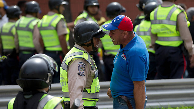 מפגין מתעמת עם שוטר בקרקאס. ונצואלה (צילום: AP) (צילום: AP)