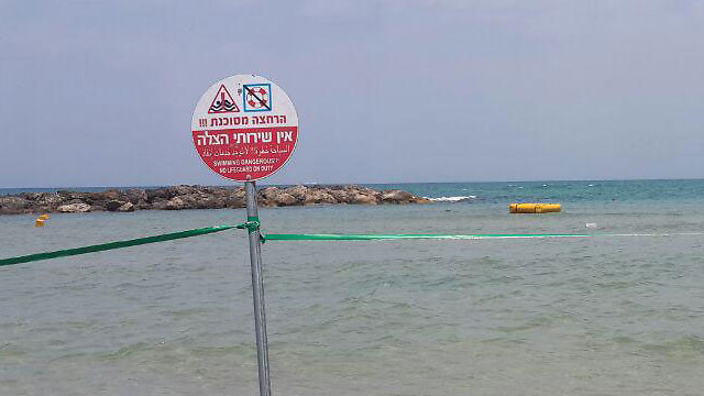 השלט שמתריע כי אין שירותי הצלה בחוף הרצליה בנתניה ()