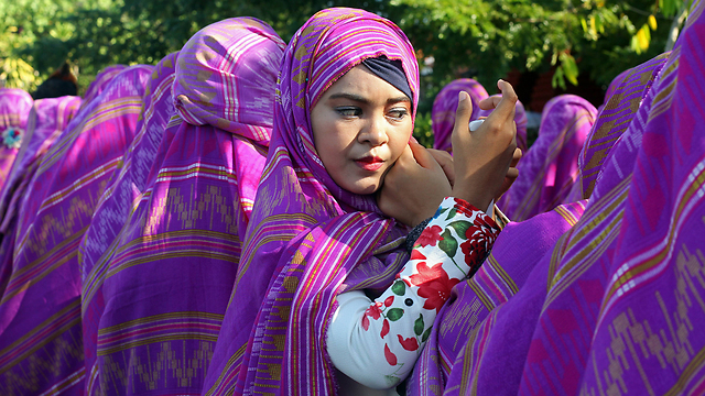אישה מסדרת את החיג'אב בתהלוכה באינדונזיה (צילום: AP) (צילום: AP)