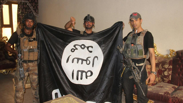 Iraqi forces with a captured ISIS flag (Photo: AP)