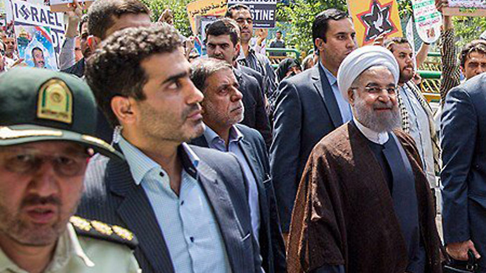 נשיא איראן רוחאני ומאחוריו שלט עם צלב קרס משולב בשם ישראל ()