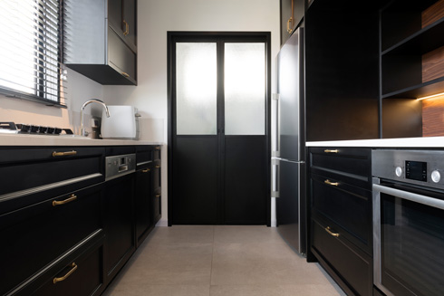 דלת אלומיניום שחורה בקצה המטבח מובילה לחדר כביסה קטן (צילום: גדעון לוין)